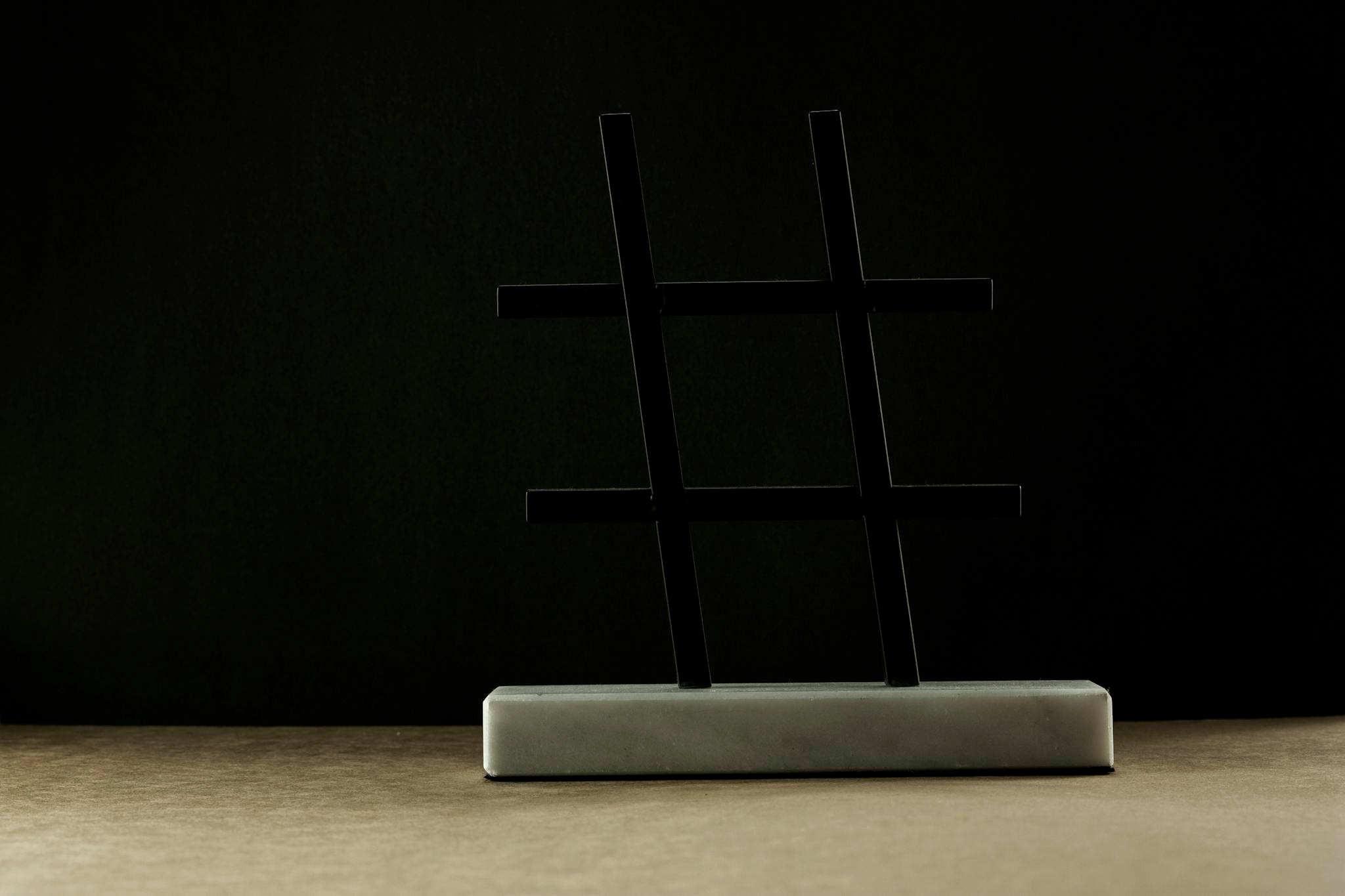 A modern hashtag sculpture in a minimalist setting with a dark backdrop.