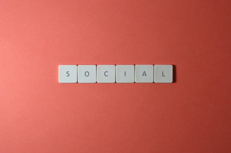 Close-up of the word 'SOCIAL' formed with tiles on a red surface, offering copyspace.
