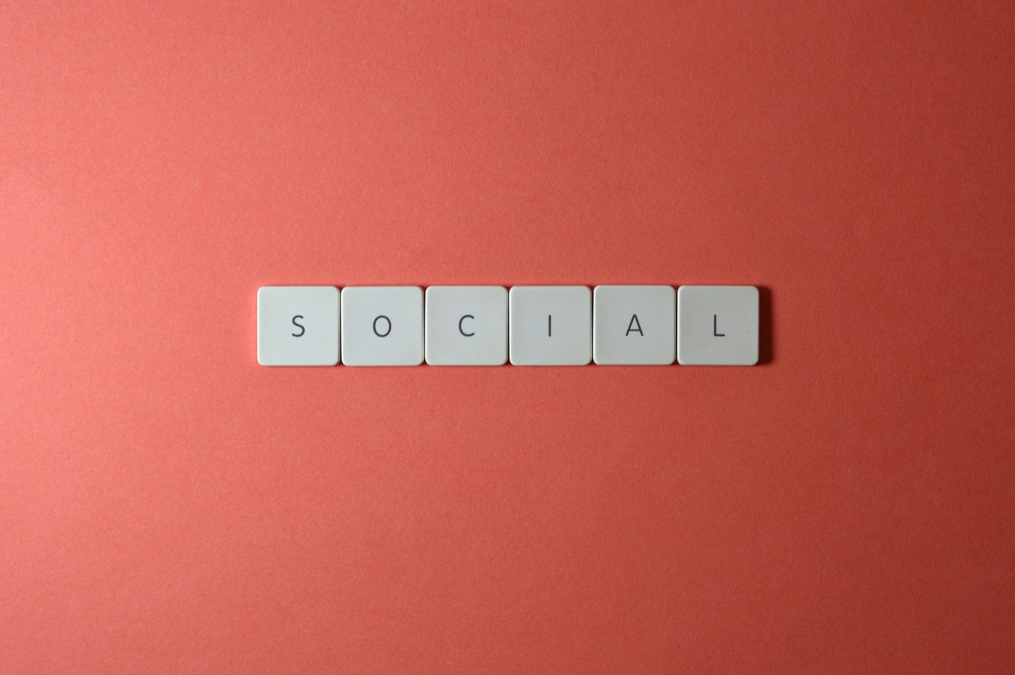 Close-up of the word 'SOCIAL' formed with tiles on a red surface, offering copyspace.